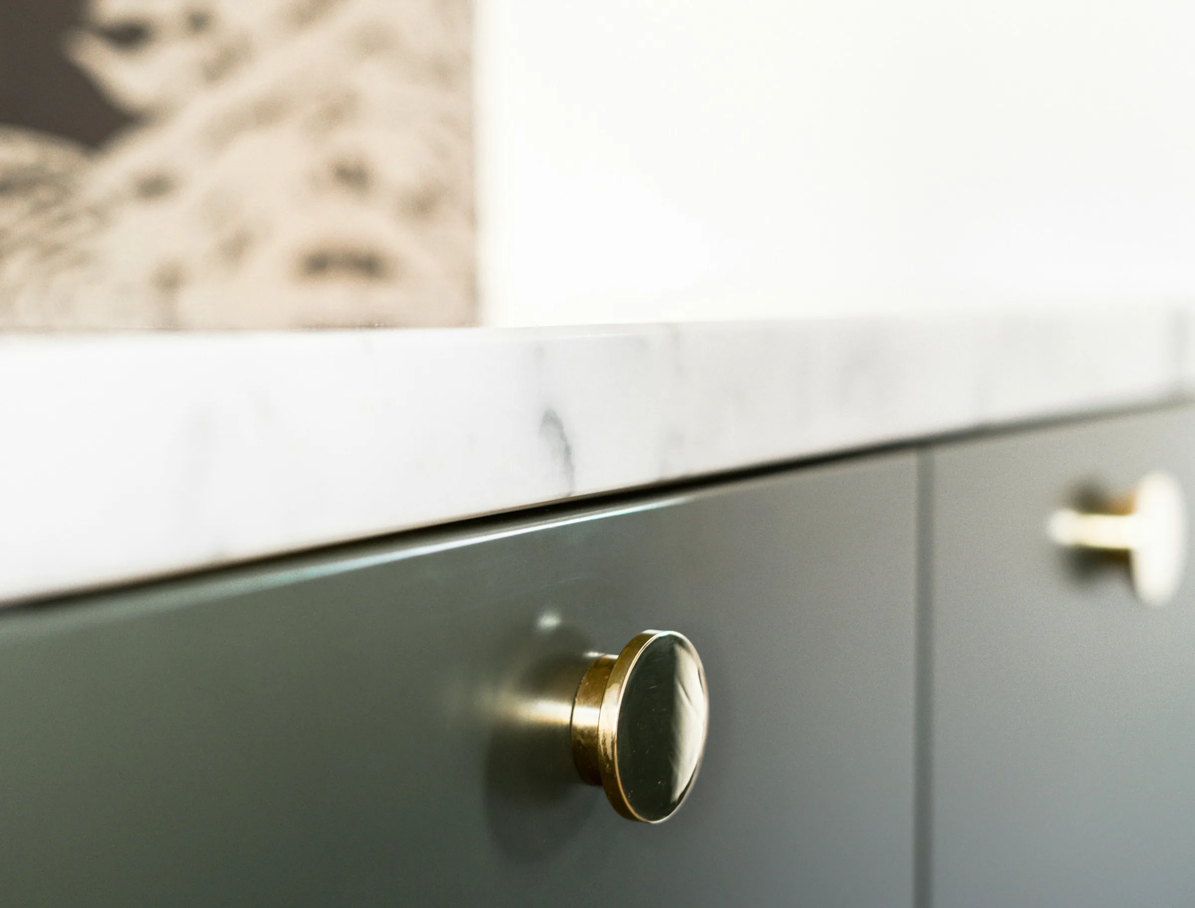 Brass knob on a green cabinet door beneath a marble top