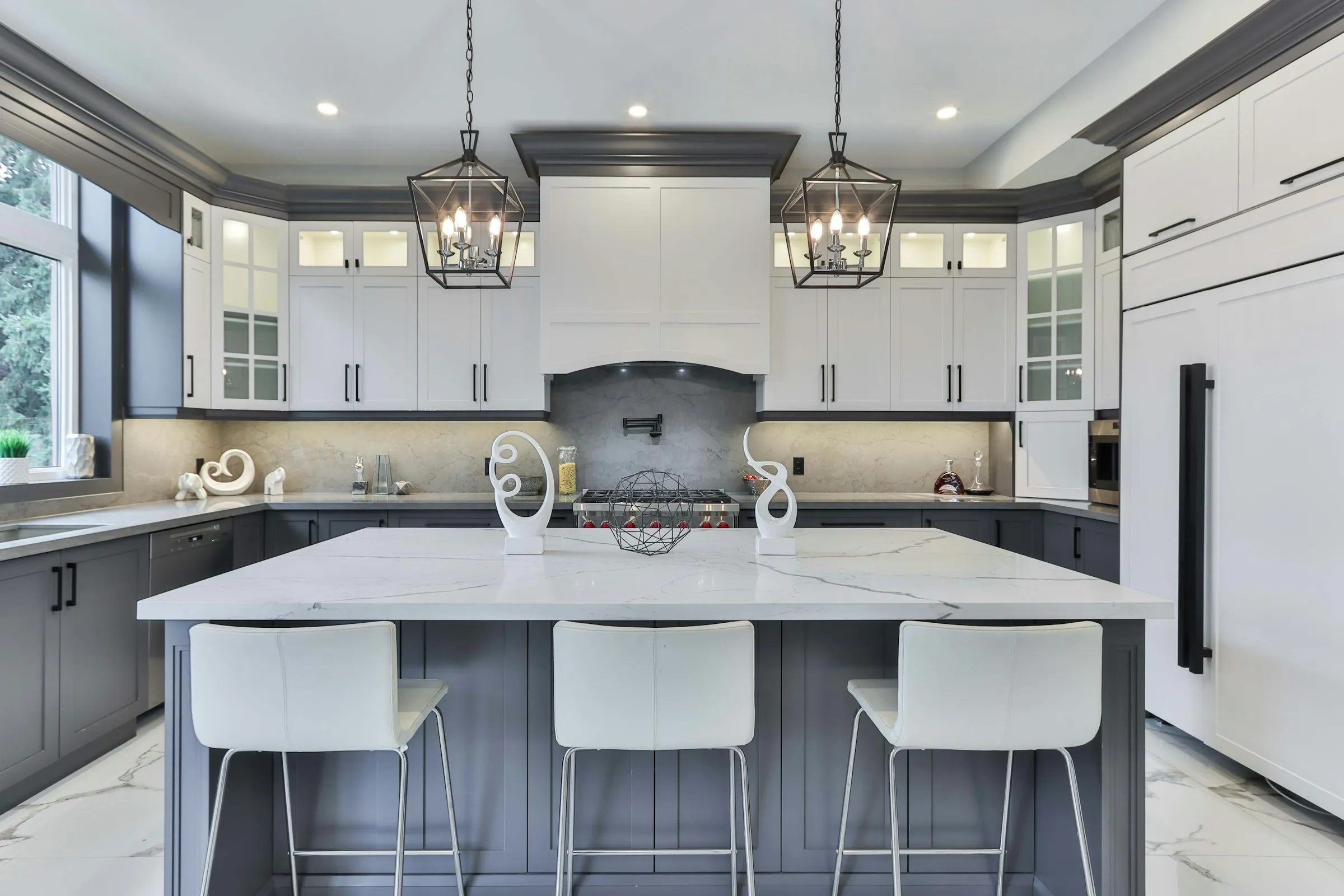 White perimeter cabinetry with a navy island under lantern pendants